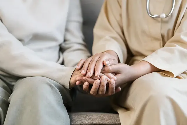 Ärztin hält tröstend die Hände einer Patientin